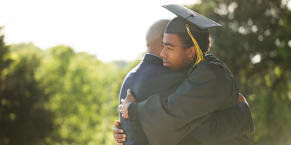 Father and son embracing in a hug after graduation